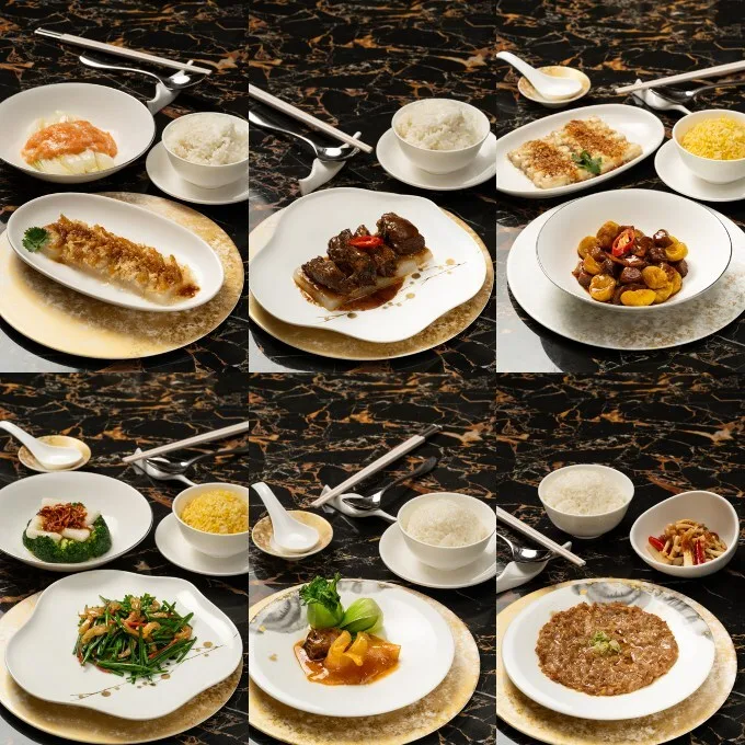 Nine plates of assorted Chinese dishes with rice and soup, arranged neatly in a grid on a dark marble table—each setting includes cutlery, a gold-trimmed plate, and the refined touch of Cathay Pacific coffee served alongside.