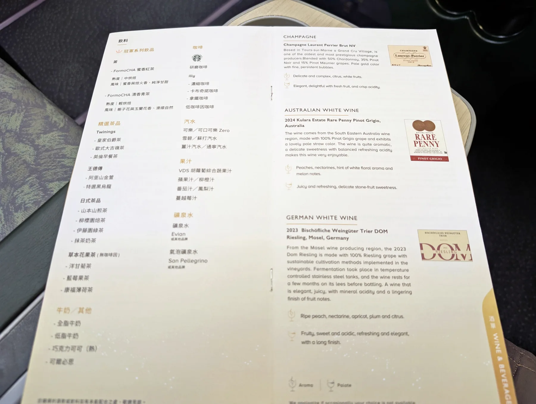 A close-up of an in-flight wine and beverage menu featuring selections of champagne, Australian white wine, and German white wine, with descriptions and gold accents on the page.