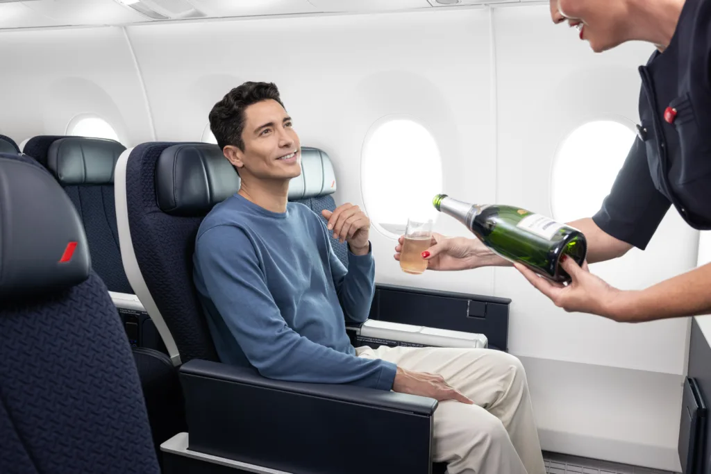 A passenger sitting in an aeroplane seat is being served a glass of champagne by a flight attendant, showcasing the luxury that comes with Korean Air awards.